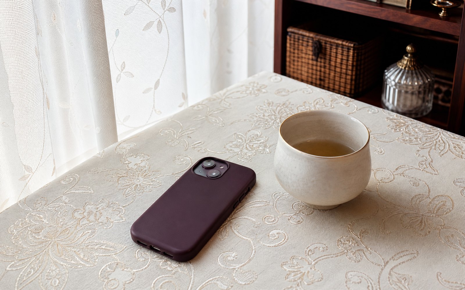 テーブルに伏せて置かれたスマートフォンと、冷めかけたカップ